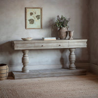 Wooden console table with decorative items against a neutral wall.