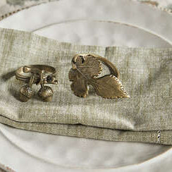 Bronze acorn and leaf napkin ring on a textured napkin with a woven placemat.