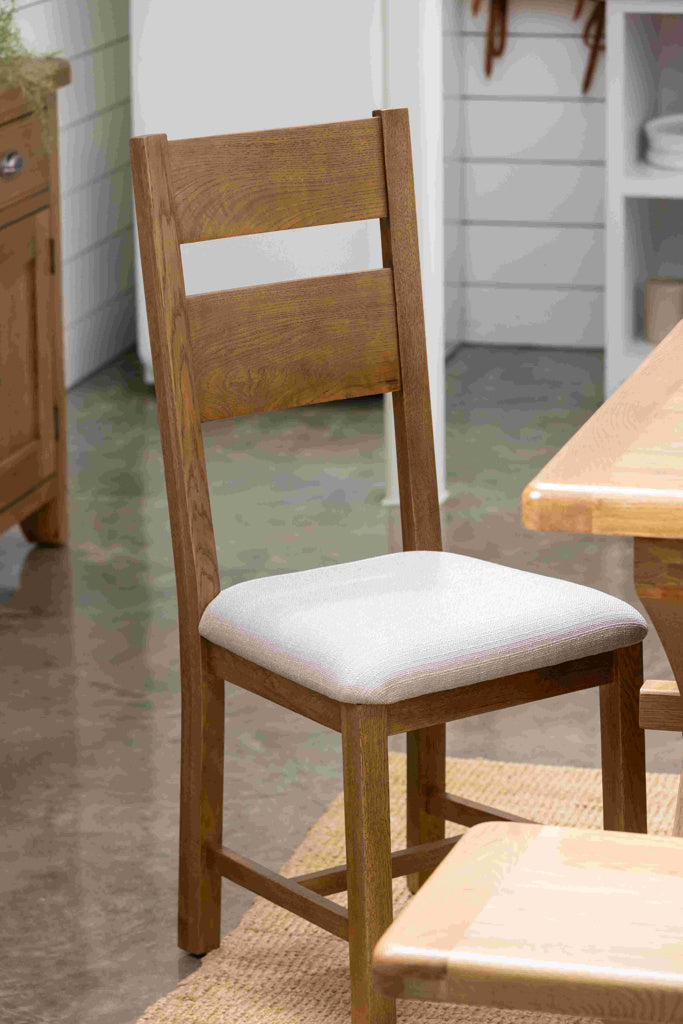 Wooden chair with a white cushion on a wooden floor.