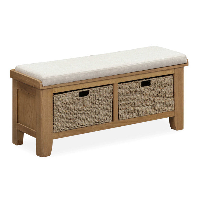 Wooden bench with a white cushion and two wicker storage baskets on a white background