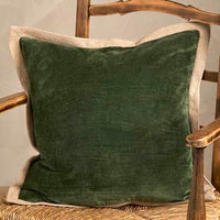 Green pillow on a wooden chair against a neutral wall