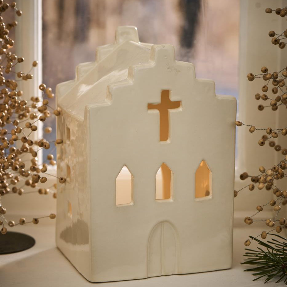 Decorative church-shaped lantern with a cross on a window