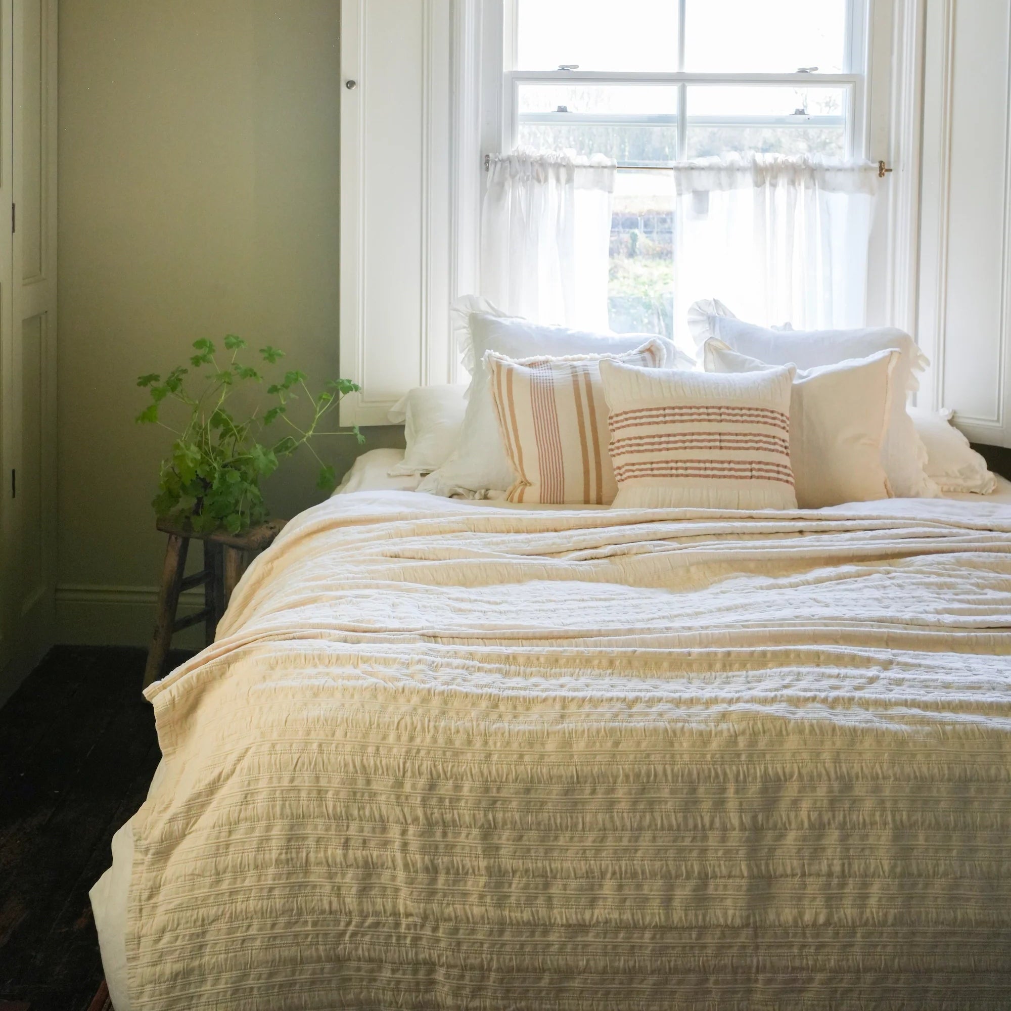 Bedroom with a bed, pillows, and a window with sheer curtains.