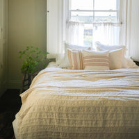 Bedroom with a bed, pillows, and a window with sheer curtains.