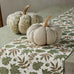 Decorative table setting with pumpkins and a patterned table runner on a table.