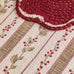 Close-up of a textured fabric with floral patterns and a scalloped edge.