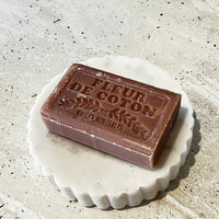 Bar of soap with 'Fleur de Coton' branding on a textured surface