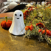 Decorative ghost and pumpkin on a table with a festive background