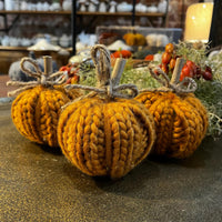 Knitted pumpkins with twine bows on a textured surface