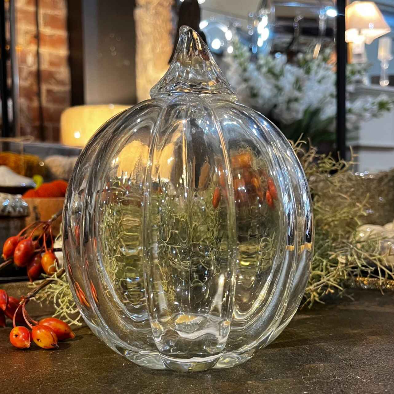Clear glass pumpkin decoration on a surface with blurred background