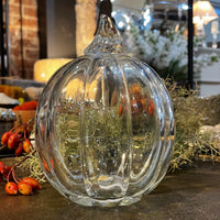 Clear glass pumpkin decoration on a surface with blurred background