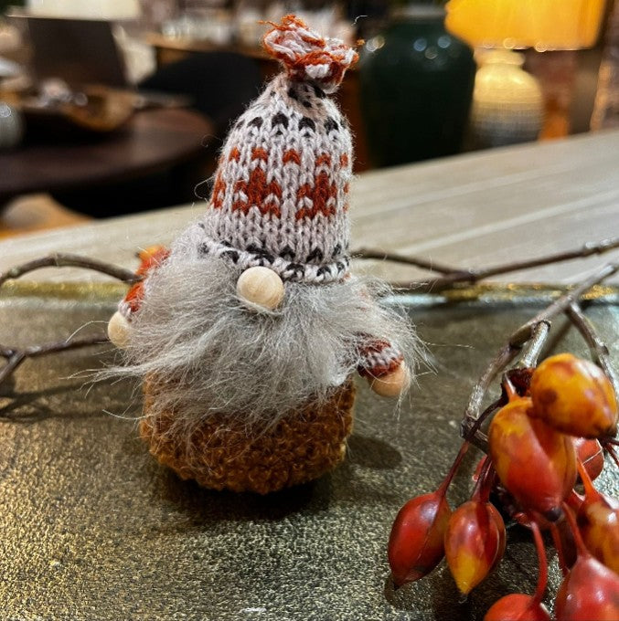 Decorative gnome with a knitted hat on a table with autumn decorations