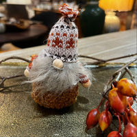 Decorative gnome with a knitted hat on a table with autumn decorations
