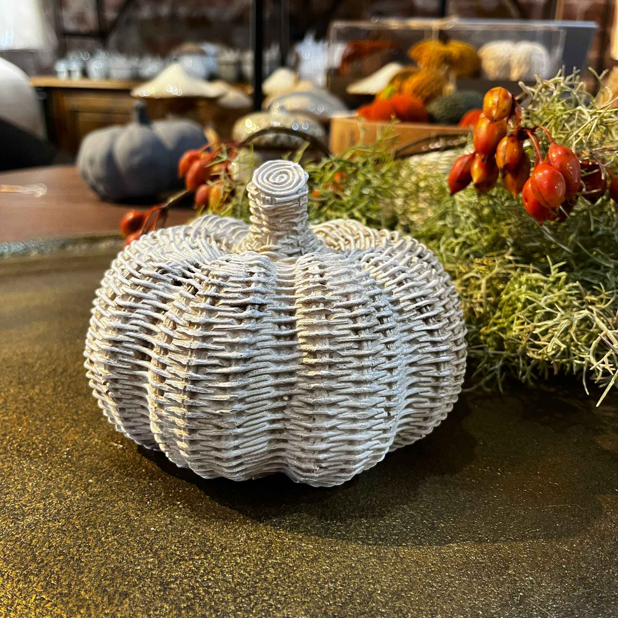 Decorative woven pumpkin on a table with autumn decorations in the background
