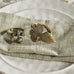 Bronze acorn and leaf napkin ring on a textured napkin with a woven placemat.