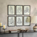 Set of six framed leaf prints on a wall above a console table with candles and decor items.