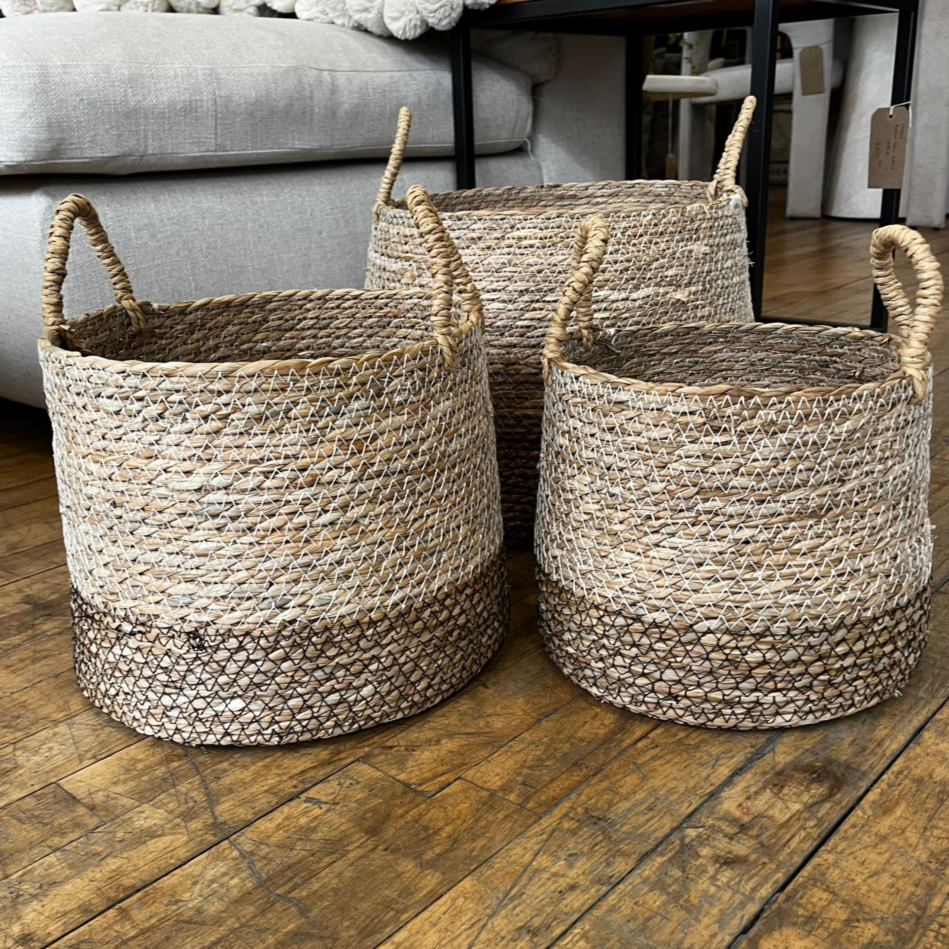 Three woven baskets on a wooden floor with a neutral background