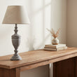 Table lamp with a textured gray base and beige lampshade on a white background
