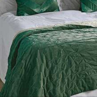 Green quilted bedspread on a bed with white bedding and green pillows.