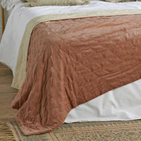 Rose Pink textured blanket on a bed with white bedding in a bedroom setting.