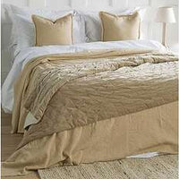 Beige comforter on a bed with white pillows in a bedroom setting