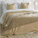 Beige comforter on a bed with white pillows in a bedroom setting