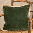 Green pillow on a wooden chair against a neutral wall